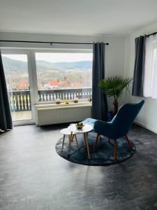 Plaue的住宿－Ferienwohnung am Tor zum Thüringer Wald 2，客厅配有蓝色椅子和桌子