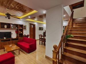 a living room with a red couch and a staircase at Windflower Villa in Mussoorie