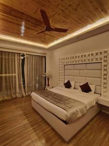 a bedroom with a large bed with a ceiling fan at Windflower Villa in Mussoorie