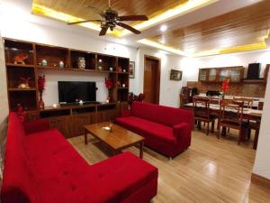 a living room with red furniture and a dining room at Windflower Villa in Mussoorie