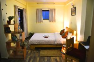 um pequeno quarto com uma cama e uma janela em Tanani Newa Home -Dhaulagiri em Patan