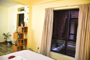um quarto com uma cama e uma grande janela em Tanani Newa Home -Dhaulagiri em Patan