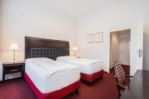 duas camas num quarto de hotel com uma mesa e cadeiras em EA Hotel Tosca em Praga