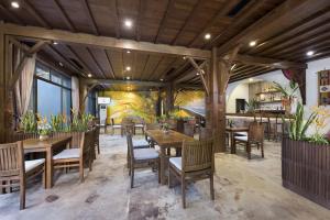 restauracja z drewnianymi stołami i krzesłami oraz malowidłem ściennym w obiekcie Serena Kim Boi Resort - Hoa Binh w mieście Hòa Bình