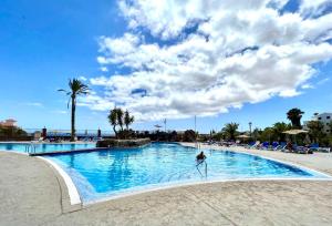 una persona está de pie en el agua en una piscina en Family Apartment by the sea, Wifi, heated pool in South of Tenerife, en San Miguel de Abona