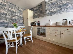 a kitchen with white cabinets and a table with chairs at Fayvan Apartments in Whitby