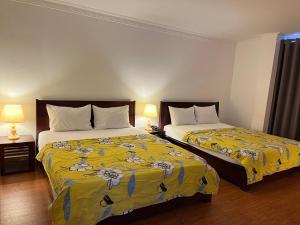 Habitación de hotel con 2 camas con sábanas amarillas en Phung Long Hotel, en Ho Chi Minh