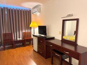 a room with a dresser with a mirror and a bedroom at Phung Long Hotel in Ho Chi Minh City