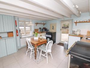 uma cozinha com uma mesa de madeira e cadeiras brancas em The Bathing House em Ashsprington