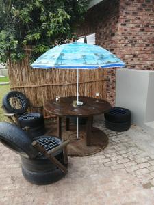 una mesa con una sombrilla azul y una silla en Petite Selfcatering Accommodation Struisbaai SA, en Struisbaai