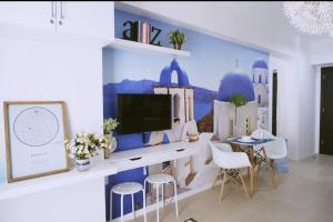a living room with a tv on a wall at Santorini at Vertis North in Manila