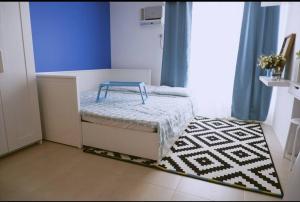 een kleine kamer met een klein bed en een tapijt bij Santorini at Vertis North in Manilla