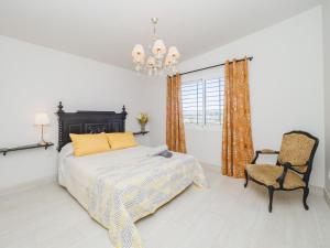 una camera con letto, sedia e lampadario a braccio di Cubo's Casa Flor High Privacy & Pool ad Alhaurín el Grande