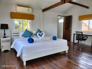 a bedroom with a large white bed with blue accents at Sand Terrace Beach Bungalows in Baan Tai