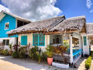 Casa azul y blanca con techo de paja en Sand Terrace Beach Bungalows, en Baan Tai