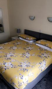 two beds in a bedroom with a yellow blanket with flowers at Carnegie Lodge Hotel in Tain
