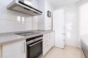 eine weiße Küche mit Herd und Spüle in der Unterkunft ApartUP Patacona Sunrise Duplex in Valencia