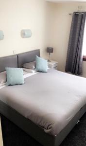 a bed with two blue pillows on top of it at Carnegie Lodge Hotel in Tain