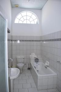 a white bathroom with a toilet and a tub and a sink at Central Hotel Omaruru in Omaruru