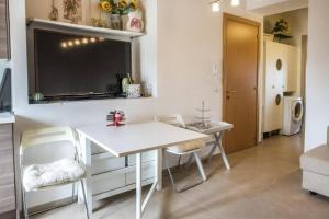 a kitchen with a white table and chairs and a tv at Grazioso Bilocale a 5 minuti da Numana in Numana