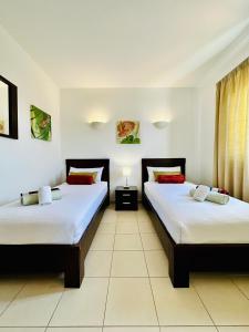 2 letti in una camera con pareti bianche di Spacious Apartment @MeliaTortugaResort a Prainha