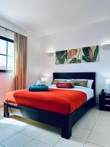 a bedroom with a large bed with a red blanket at Spacious Apartment @MeliaTortugaResort in Prainha