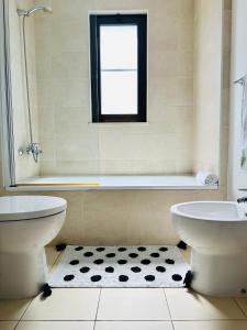 łazienka z 2 toaletami, wanną i oknem w obiekcie Spacious Apartment @MeliaTortugaResort w mieście Prainha
