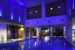 a large room with a swimming pool with blue lights at Novotel Cardiff Centre in Cardiff