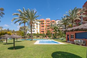 een resort met een zwembad en palmbomen bij Apartamento de diseño 2 terrazas en Estepona by Rent Me in Estepona