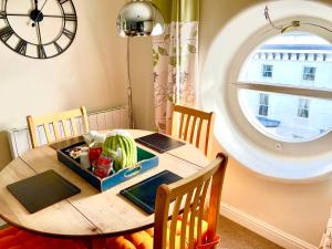 a dining room table with a clock on the wall at Fayvan Apartments in Whitby