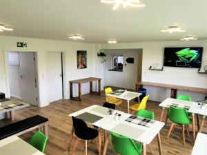 une salle à manger avec des tables blanches et des chaises vertes dans l'établissement Speedys Bed & Breakfast, à Reimerath