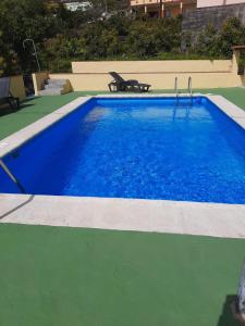 Monte de Breña的住宿－Casitas Conchi A，旁边设有长凳的大型蓝色游泳池