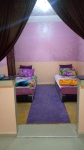 two beds in a room with purple walls at DAKHLA in Dakhla