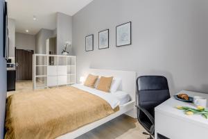 a white bedroom with a bed and a chair at Warsaw City Apartments in Warsaw