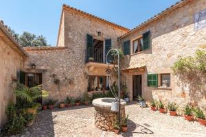 une maison en pierre avec une fontaine dans la cour dans l'établissement S'alzinaret, lujosa Villa con piscina, à Bunyola