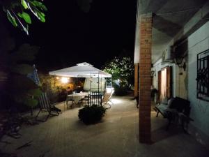 un patio con una mesa y una sombrilla por la noche en Dimora Buglio Valguarnera, en Valguarnera Caropepe