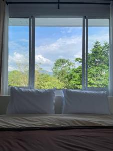 a bed with white pillows in front of a window at The Triple M Mountain Resort in Ban Muang Ton Mamuang