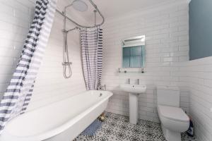 een badkamer met een bad, een toilet en een wastafel bij The Old Concert Hall - Norfolk Cottage Agency in Holt