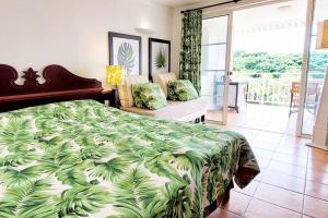 ein Schlafzimmer mit einem Bett mit einer grünen und weißen Decke in der Unterkunft Studio "Prestige" Sainte Luce in Sainte-Luce