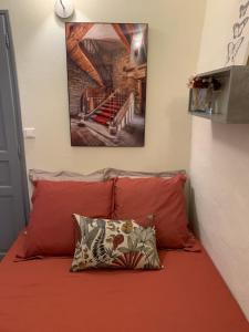 a bed with red pillows and a picture on the wall at Lou Magnan in L'Isle-sur-la-Sorgue