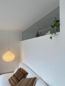 Habitación blanca con almohada y lámpara en Sonnenloft Else und Studio Luise, en Neubeuern