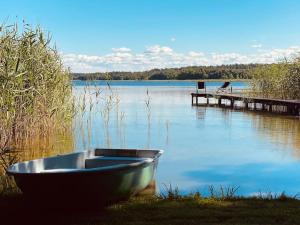 a boat sitting on the grass next to a dock at Siedlisko Dziki Gil na Mazurach z prywatną plażą i SPA! in Ruś