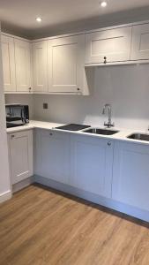 a kitchen with white cabinets and a sink at Filton 6 BDR House for contractors & families. in Bristol