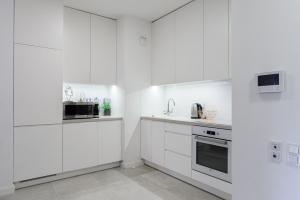 a white kitchen with white cabinets and appliances at Lumina luxury apartments in Mennica Residence in Warsaw