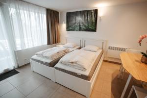 um quarto branco com 2 camas e uma mesa em Apparts Simee-Les Terrasses de Malmedy em Malmedy