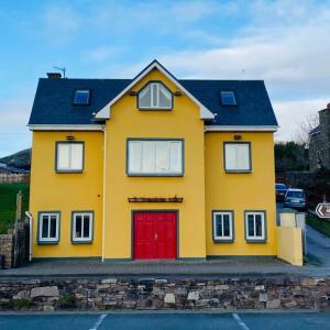 żółty dom z czerwonymi drzwiami w obiekcie Dingle Marina Lodge w mieście Dingle