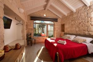 a bedroom with a red bed in a stone wall at Trulli in corte in Alberobello