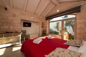 - une chambre avec un lit rouge et une grande fenêtre dans l'établissement Trulli in corte, à Alberobello