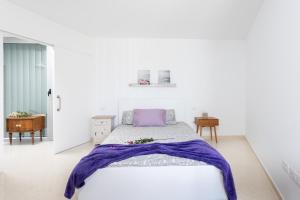 um quarto branco com uma cama com um cobertor roxo em Home2Book Cozy & Relax House in Güímar, Terraces em Güímar