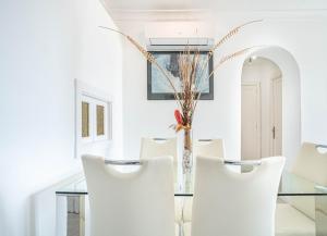 阿尔库迪亚CARABELA 94的一间设有玻璃桌和白色椅子的用餐室